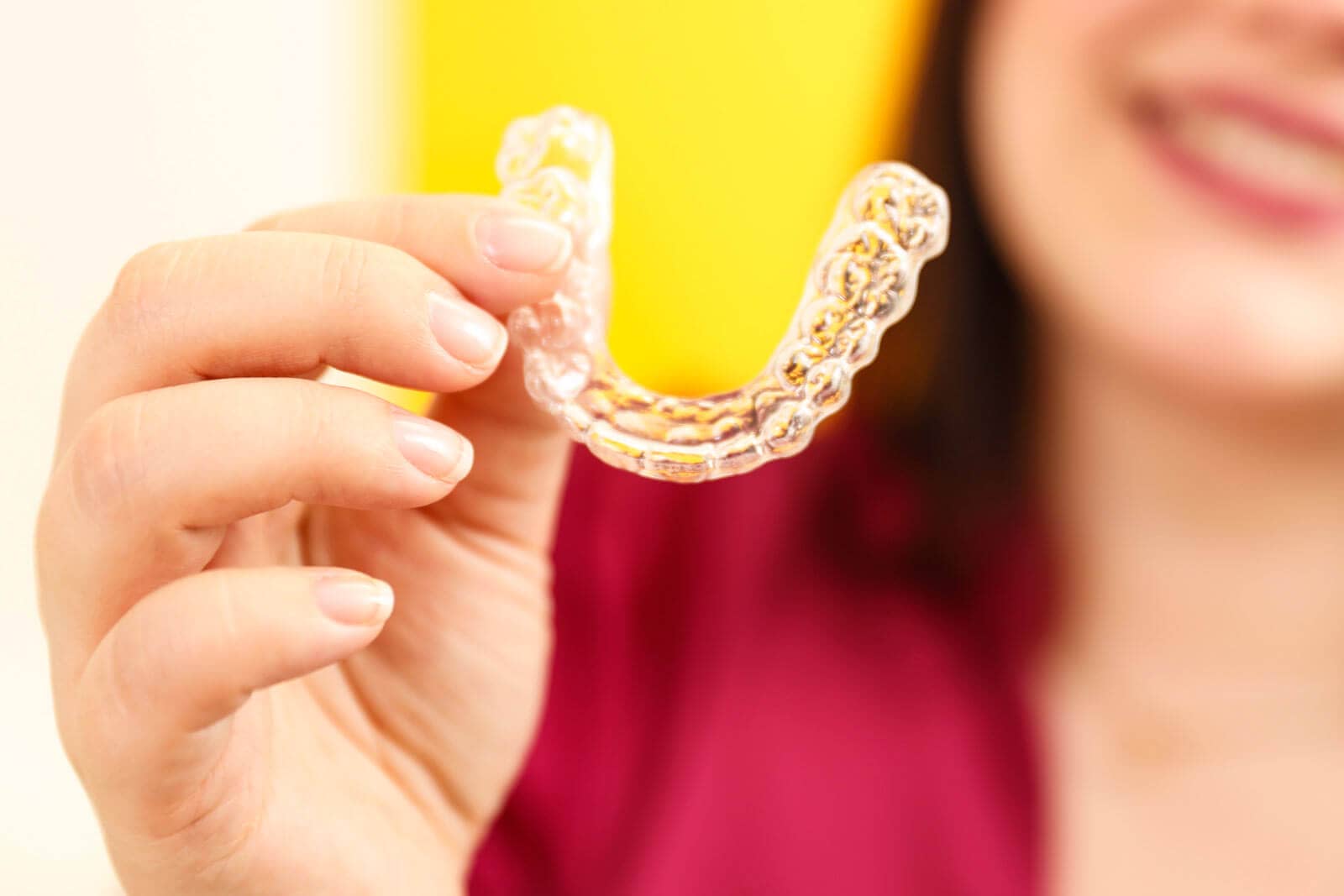 A woman holds the transparent braces into the camera