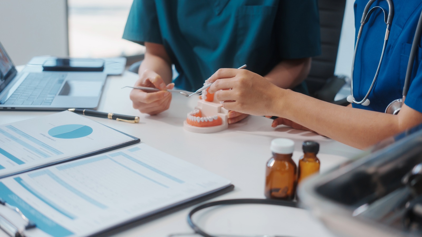 Zwei Ärzte erklären an einem Kiefermodell, was bei einer anstehenden OP gemacht wird.