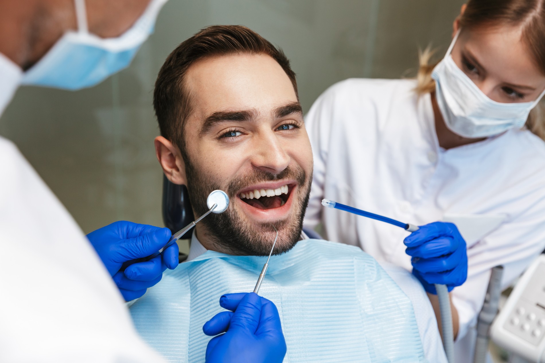 Handsome happy young man sitting in medical dentist center.